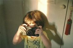 a young boy taking a selfie in front of a mirror