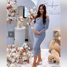 a pregnant woman standing in front of a display of flowers and teddy bears at a baby shower