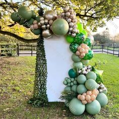 a large balloon arch in the shape of a tree with balloons on it and greenery