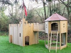 a wooden play set with a tower and ladder in the grass next to some trees