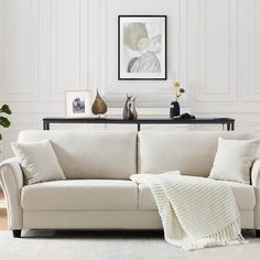 a living room with a white couch and some pictures on the wall next to it