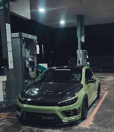 a green car is parked at a gas station