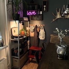 a room filled with lots of clutter and furniture next to a neon sign that reads love