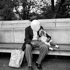 a man sitting on a bench with a baby in his lap and a balloon attached to his head