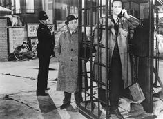 two men standing next to each other in front of a telephone booth