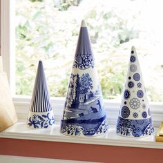 three blue and white ceramic cones sitting on a window sill