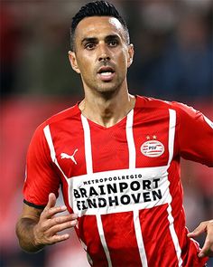 a man in a red and white shirt is playing soccer