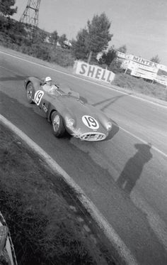 an old photo of a race car driving down the road in front of a person
