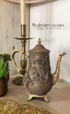 a silver tea pot sitting on top of a table next to a candelabra