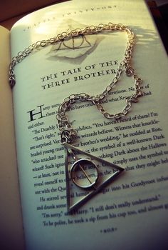 an open book with a harry potter necklace on it