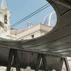 a clock tower is seen through the roof of an outdoor structure in front of a building