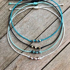 three bracelets with beads on top of a wooden floor