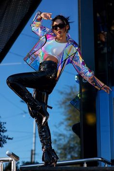 a woman in black leather pants and a white shirt is posing for the camera with her arms outstretched