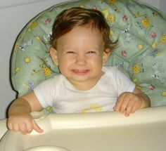 a baby sitting in a high chair smiling