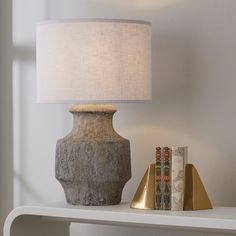 a table lamp sitting on top of a white shelf next to a bookshelf