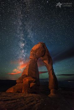 the night sky is filled with stars, and there are rocks in front of it