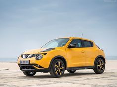 a yellow nissan juke is parked on the beach