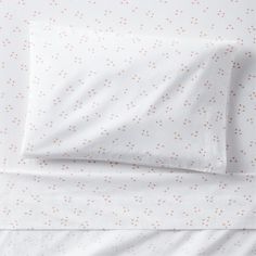 an image of a bed with white sheets and orange polka dots on the sheet set