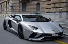 a silver sports car parked in front of a building on the side of a street