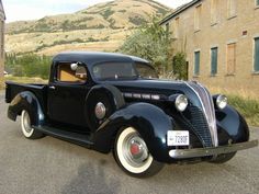 an old black car parked in front of a building