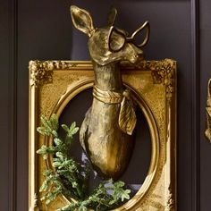 a golden deer head mounted to the side of a wall