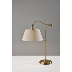 a lamp that is on top of a white table with a gray wall in the background