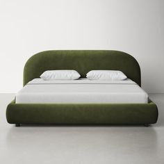 a green bed with white sheets and pillows on it's headboard, sitting in front of a wall
