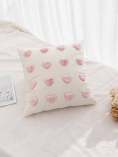 a white pillow with pink hearts on it next to a bouquet of flowers and a card