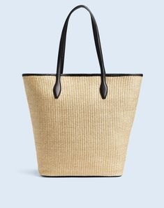 a straw tote bag with black handles
