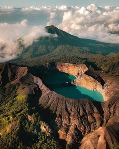 an aerial view of a lake surrounded by mountains and clouds in the distance with blue water