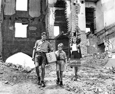 an old black and white photo of three people walking in front of a destroyed building