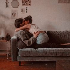 two people sitting on a couch with their arms around each other and one person kissing