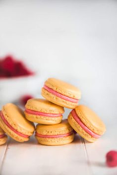 a stack of macaroons sitting on top of a white counter next to raspberries