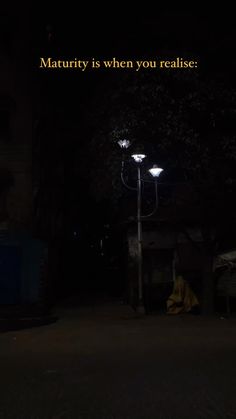 a person sitting on the ground under a street light at night with text reading, maturity is when you reade