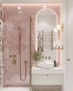 a bathroom with pink tiles and gold fixtures on the walls, along with a white sink