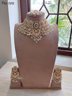 a necklace and matching earrings on display in front of a window with a wooden table