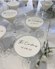 there are many wine glasses on the table with names and date written on them for guests to drink