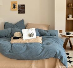 an unmade bed with blue and white striped comforter, pillows and pillow cases