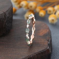 a ring with green and white stones on top of a wooden table next to dried flowers