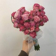 a person holding a bouquet of pink roses