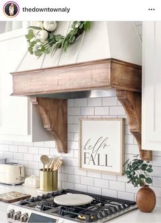 a kitchen with white cabinets and a wooden shelf above the stove top that says hello fall