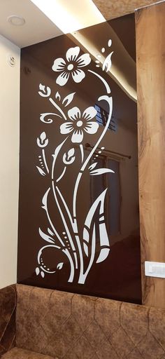 a glass wall with flowers painted on it in the corner of a room next to a couch