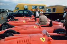 some people are standing around an orange race car