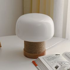 a white lamp sitting on top of a table next to an open book