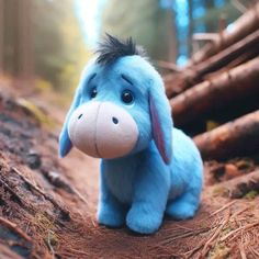 a blue stuffed animal sitting on top of a forest floor