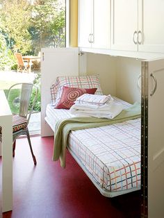 a bed sitting in a bedroom next to a window with lots of pillows on top of it