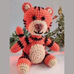 a crocheted stuffed animal sitting next to a plant