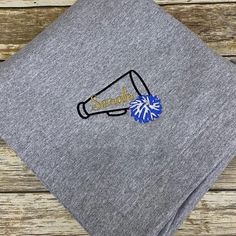 a gray t - shirt with a blue and white cheer megaphone on it