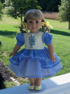 the doll is wearing a blue and white dress