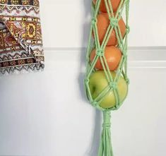 an oranges and apples are in a green net hanging on the wall next to a towel